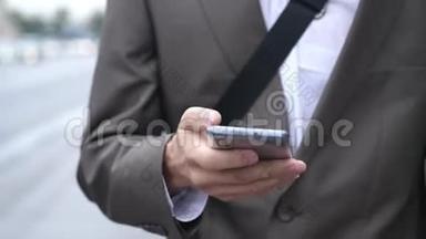 商人在户外使用触摸手机，关门，男人在街上用手机走路。